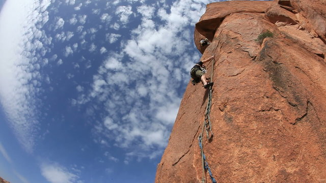 A female climber belays the leader during a rock climbing in Tafraoutte, Morocco, Africa.,