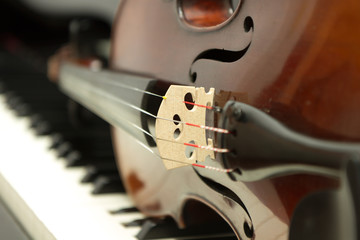 Violin lying on a grand piano keyboard