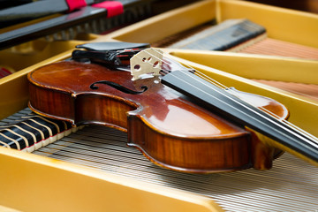 Dusty violin lying inside grand piano on strings