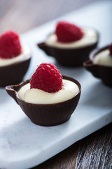 Dark chocolate cup filled with cream and raspberry