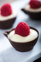 Dark chocolate cup filled with cream and raspberry