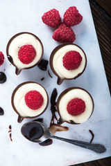 Dark chocolate cup filled with cream and raspberry