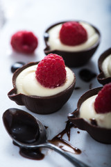 Dark chocolate cup filled with cream and raspberry