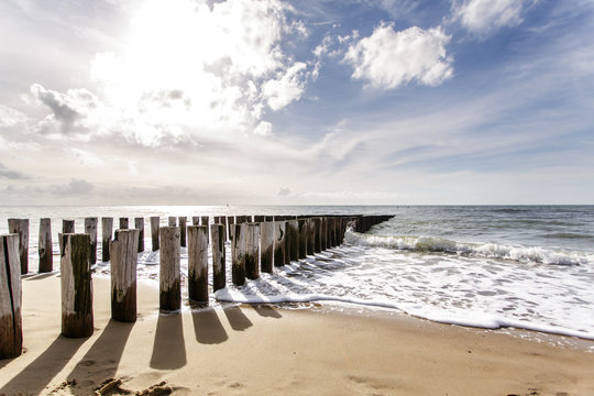 Wellenbrecher am Niederl&auml;ndischen Nordseestrand im Licht der tiefstehenden Sonne mit langen Schatten und sch&ouml;ner Meeresbrandung