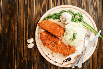 
meat with garnish , chicken cutlets in breadcrumbs , boiled mashed potatoes with herbs , garlic and spices on a wooden background
