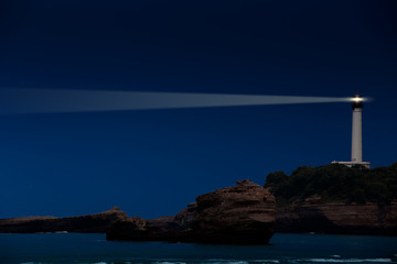 White lighthouse tower beaming in the night