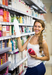 Woman choosing shampoo at store.