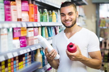 Man selecting shampoo in the store.