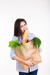 Beautiful hungry  young woman holding paper bag with groceries and having fun