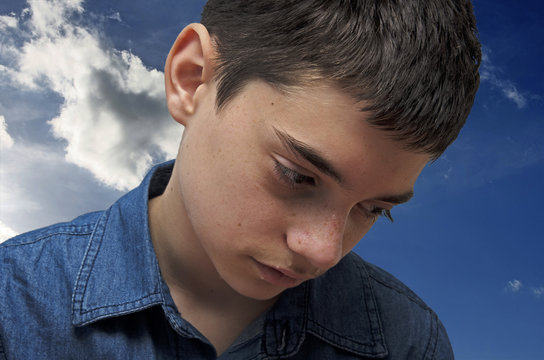 Sad Boy.Caucasian Teenager In Deprecion Crying On A Cloudy Sky Background.