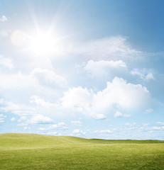 Fototapeta na wymiar Empty field of green grass, sun light shining in blue sky