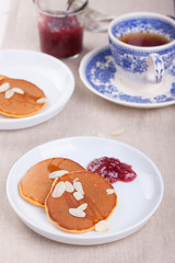 Pumpkin pancakes with honey, nuts and jam in a white plate on a table.