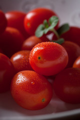 Cherry tomatoes in a white plate on a black background. closeup.