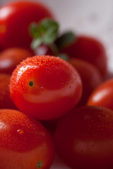 Cherry tomatoes in a white plate on a black background. Closeup.