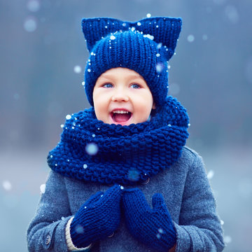 Cute Kid, Boy In Winter Clothes Playing Under The Snow