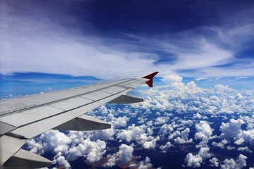Fototapeta premium Wing of an airplane flying above the clouds