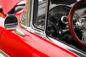 Wing mirror of a red shiny classic vintage car