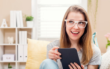 Happy young woman reading an e-book on her couch