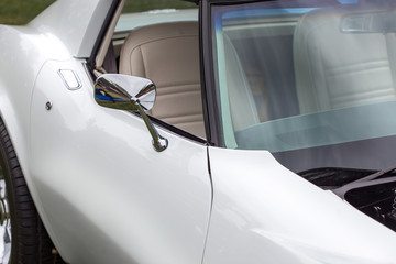 Close-up of wing mirror of a white shiny classic vintage car