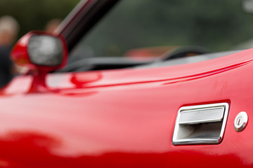Obraz na płótnie Canvas Close-up of car door of a red shiny classic vintage car