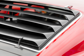 Close-up of wind radiator grille of a red shiny classic vintage car