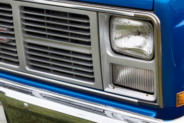 Obraz na płótnie Canvas Close-up of right headlights of a blue shiny classic vintage car