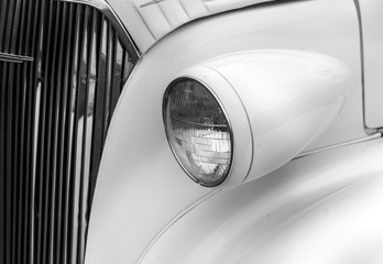 Close-up of right headlights of a white shiny classic vintage car
