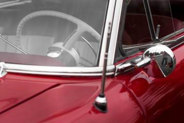Steering wheel of a maroon shiny classic vintage car