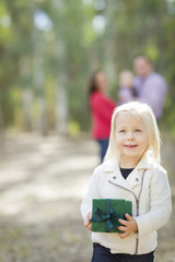 Baby Girl With Christmas Gift Outdoors Parents Behind