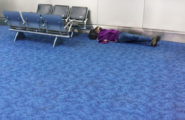 Boy sleeping on floor of at airport waiting room