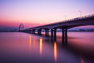 sunrise skyline and reflection of bridge over river