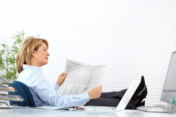 Beautiful mature business woman reading newspaper.