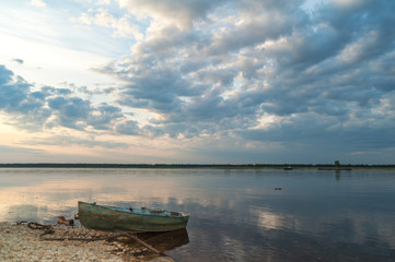 Laid up wooden boat and cargo ship against Severnaya Dvina River panorama at sunset. Bereznik settlement, Arkangelsky region, Russia.
