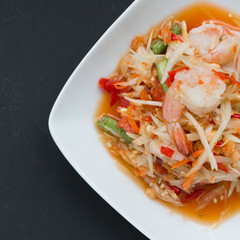 Green papaya salad (Som Tum) with shrimp on black background