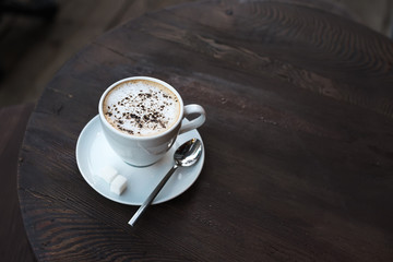 Cup of cappuccino on old dark wooden table