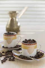 Two cups and coffee beans on the table.