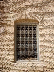 a window with a decorative bars in a brick wall