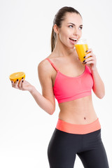 Cheerful fitness girl drinking  juice and holding half of orange