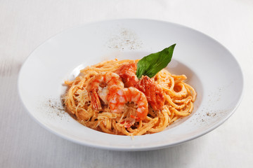 pasta with shrimp and salmon isolated on white background tomato sauce Round plate menu