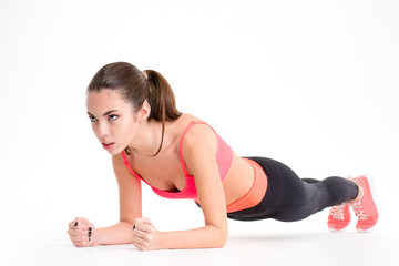 Fototapeta premium Concentrated beautiful fitness girl in sportwear exercising doing plank