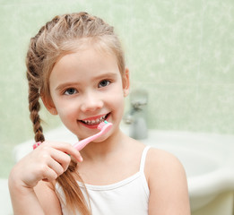 Smiling cute little girl brushing teeth