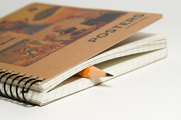 Closed notebook  and pencil on over white