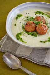 creme soup with meatballs in a white bowl on a napkin