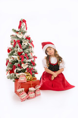 Bambina seduta con cappello e albero di Natale