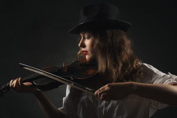 Beautiful woman playing old violin / Drak background / Studio portrait
