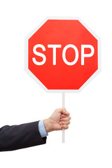 Man's hand in a blue shirt and jacket is holding a red sign STOP.