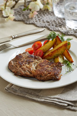 a piece of pork with sauteed potatoes and tomatoes