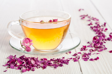 Rose tea and dried petals on white wooden table