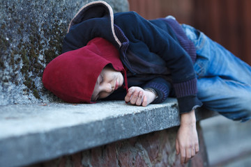 young homeless boy sleeping on the street