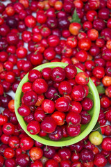 Pile of bright red acerola cherries stacked on display at an outdoor fruit and vegetable market in Rio de Janeiro, Brazil